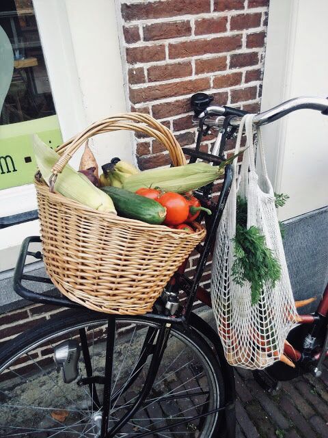 A bike with a basket of fresh vegetables and a reusable mesh produce bag